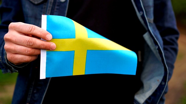 在户外举着瑞典国旗的男子。独立日，或国定假日的概念视频下载