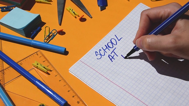 学生手画学校在家里的文字在纸记事本上，回到学校，学习用品视频素材