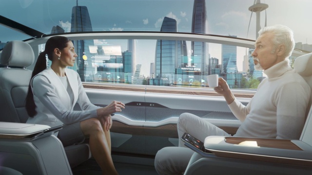 美女和老人在无人驾驶汽车里聊天。未来的自动驾驶货车正在一座玻璃摩天大楼的现代城市的公路上行驶。视频素材