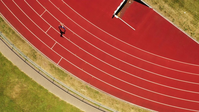 中年女性运动员在跑道上奔跑的鸟瞰图视频下载