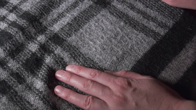 特写的女人的手处理丙烯酸或羊毛格子围巾在单色视频下载