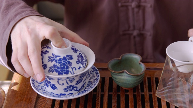 男子将热水倒在茶盖丸上，放在木托盘上冲泡。师傅用玻璃壶泡茶，传承东方茶道传统。视频素材