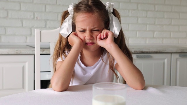 这孩子不想喝牛奶。美丽的小女孩不想吃乳制品视频素材