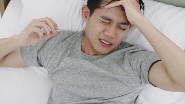 年轻人因头痛躺在家里的床上视频下载