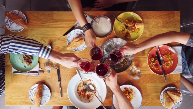 俯瞰一群朋友在木桌上喝酒吃饭。高质量4k镜头视频下载