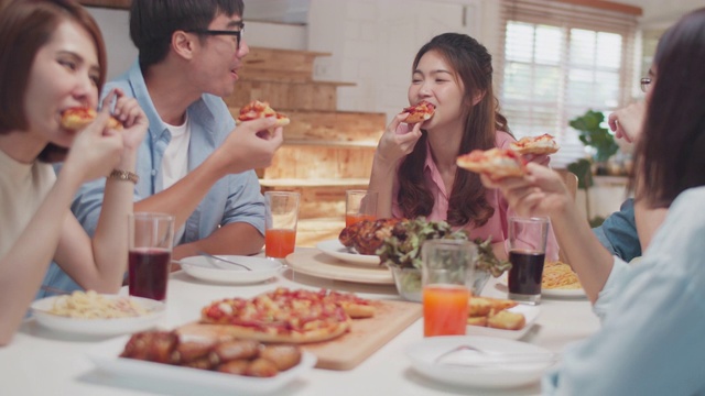 快乐的亚洲朋友有乐趣一起吃披萨在家里，朋友用餐的概念视频下载