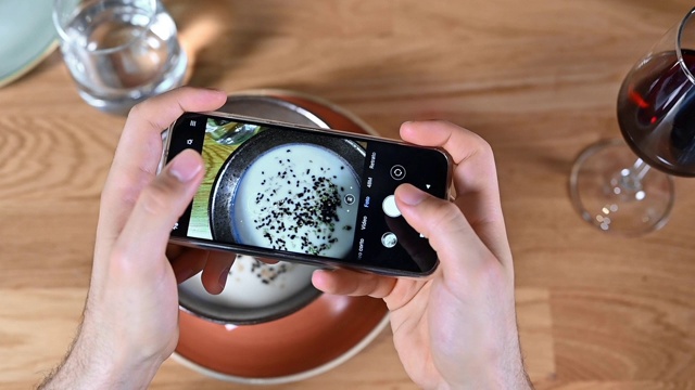 一名男子用智能手机拍摄餐馆或咖啡馆的食物。高质量的画面视频素材