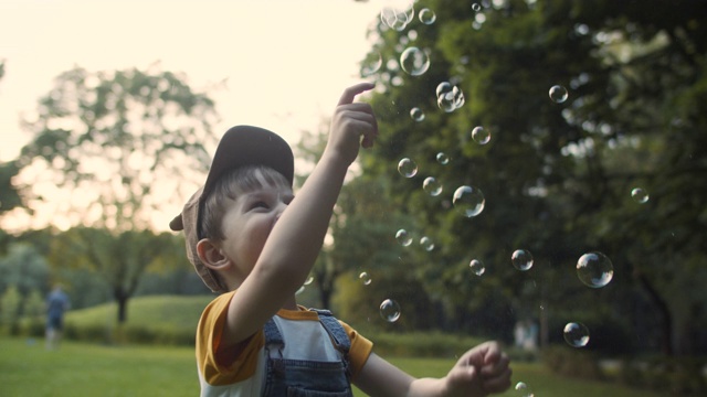小男孩在夏天的公园里抓肥皂泡视频素材
