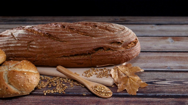 美味健康的黑麦有机面包和面包在桌子上洒谷物和木勺视频素材