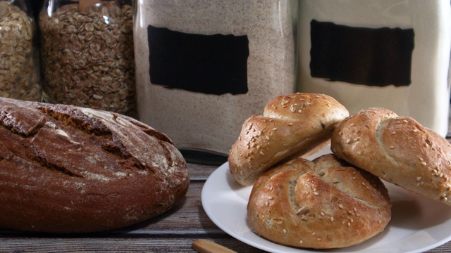 把黑麦有机面包、面粉和小面包放在桌上。近距离视频素材