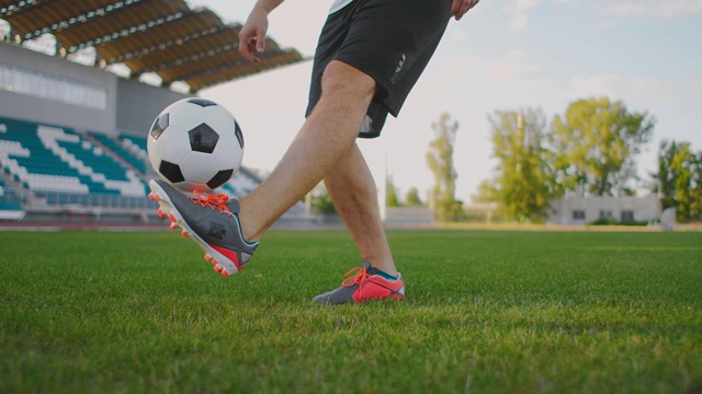 职业男子足球运动员在足球场上用慢动作玩弄足球的运动装备视频下载