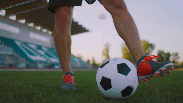 在阳光明媚的夏日，职业足球联赛男子在户外运动场上用腿抛球，用慢动作倾斜视频素材