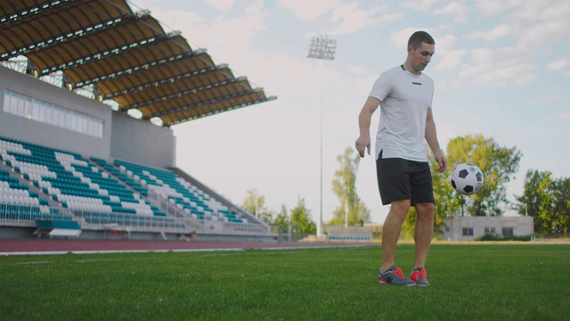 职业男子足球运动员运动员在足球场上用慢动作在运动器材上变戏法。在看台附近的体育场里踢足球的人视频素材