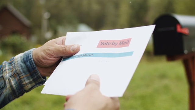 一个男人的手把信和选票投进他家附近的邮箱的特写视频素材