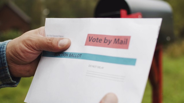 一个男人的手把信和选票投进他家附近的邮箱的特写视频素材