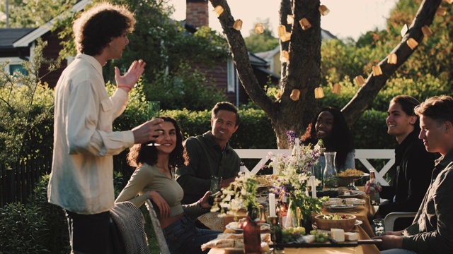 手持拍摄的男人与微笑的朋友说话，而站在桌旁的花园派对视频素材
