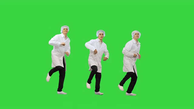 三名男医生穿着白色长袍，戴着防护帽，看着绿屏上的摄像头跳着同步舞视频素材