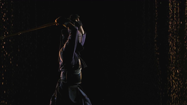 一名身穿传统服装、手持竹剑的日本剑道战士正在雨点中以黑色背景训练。关闭了。慢动作视频下载