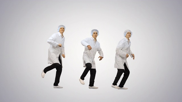 三名男医生穿着白袍，戴着防护帽，看着渐变背景的摄像机跳着同步舞蹈视频素材