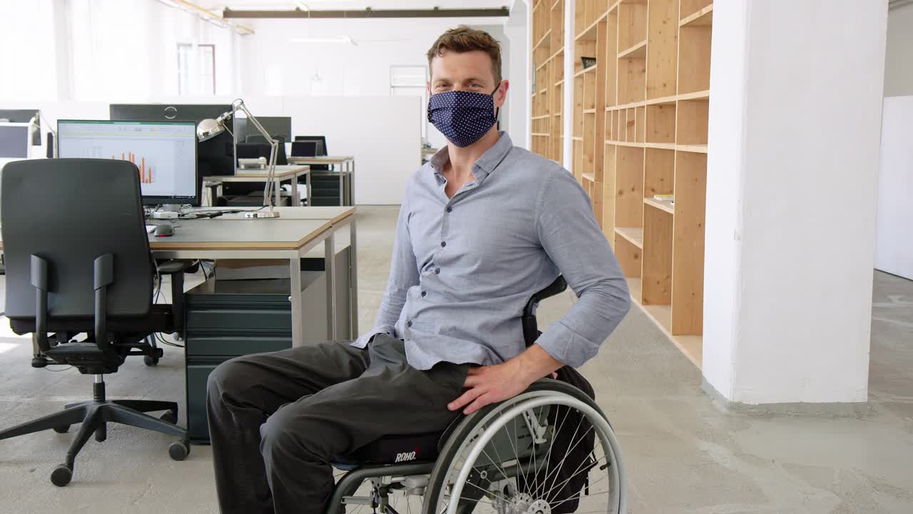 坐在轮椅上戴着口罩的商人在办公室上班视频素材