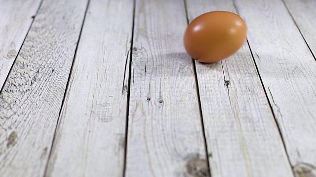 鸡蛋在木桌上滚动。慢动作视频素材
