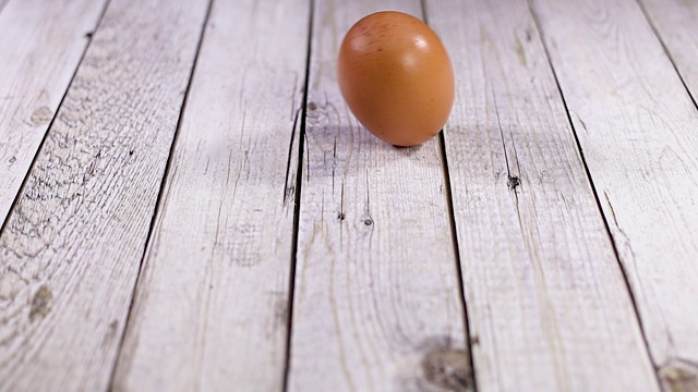 鸡蛋在木桌上滚动。慢动作视频素材