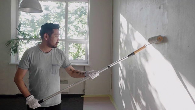 日本一名男子用油漆滚筒刷墙视频素材