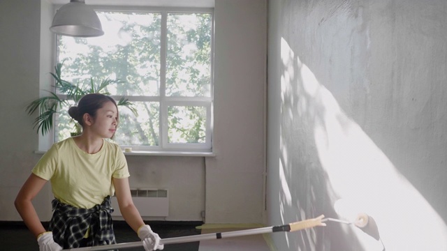 一名日本妇女在家用油漆滚筒刷墙视频素材