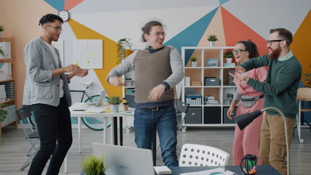 年轻人兴奋的慢镜头，同事们在工作场所跳舞，开怀大笑视频素材