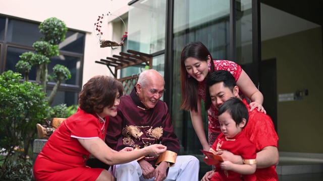 春节团圆饭后，亚洲华人家庭的老爷爷给孙子送红包红包，吃传统菜肴生鱼视频下载