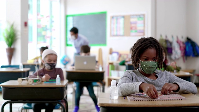 2019冠状病毒病期间，戴口罩的学生在教室里视频素材