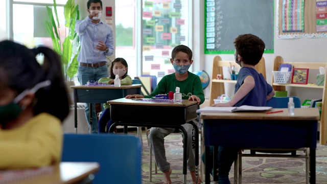 2019冠状病毒病期间，戴口罩的学生在教室里视频素材