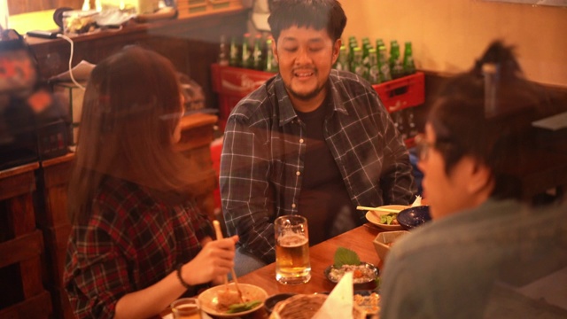 亚洲夫妇和朋友在日本居酒屋餐厅酒吧吃和喝啤酒视频素材