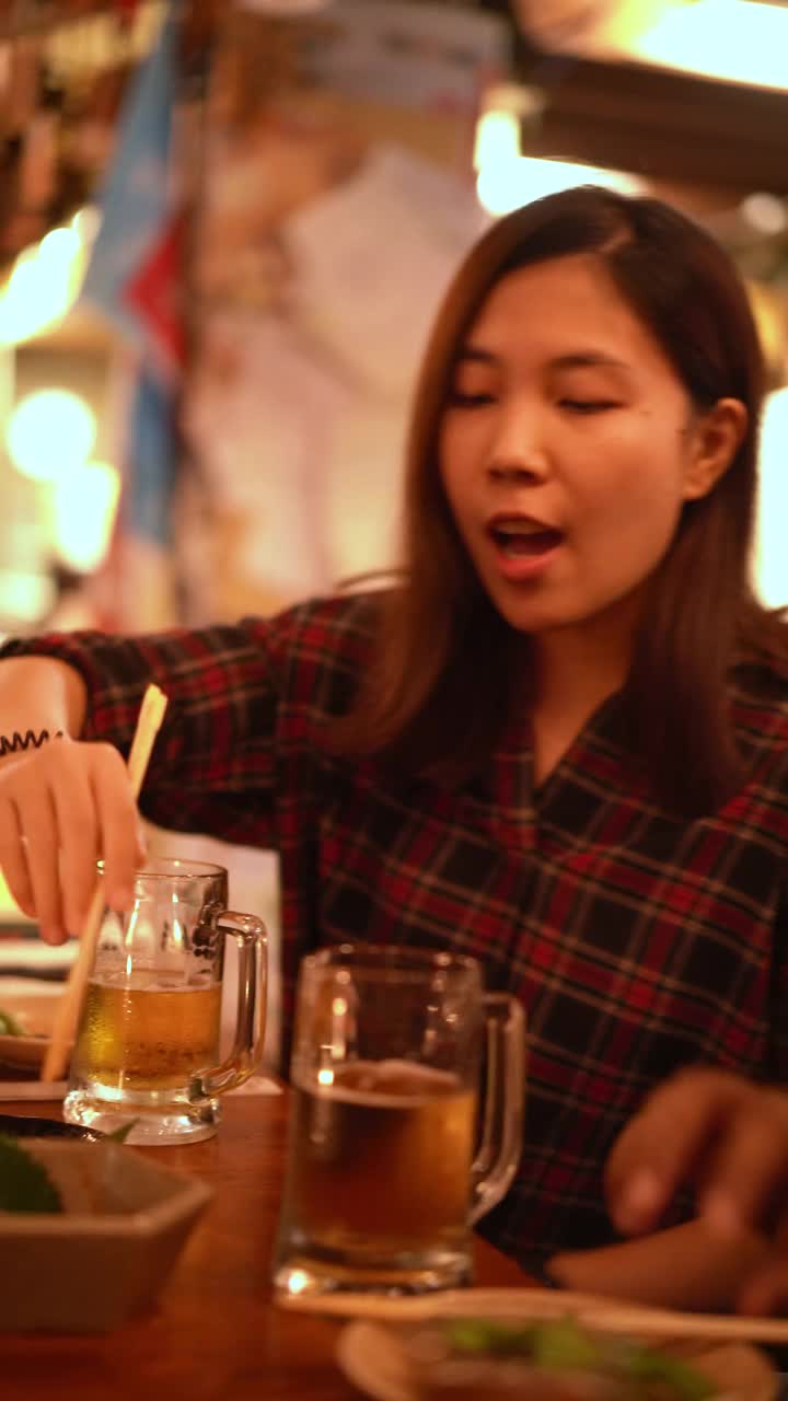 垂直亚洲女人喝酒和享受她的时间在居酒屋，日本啤酒花园酒吧视频素材