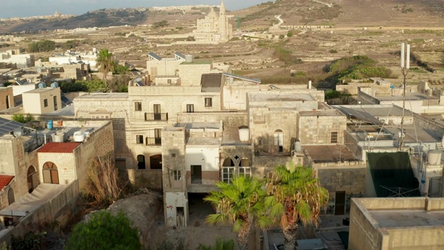 在地中海国家马耳他的太阳能电池板和屋顶平台在棕色和米色的沙子颜色，俯瞰乡村和教堂，空中向前多莉视频下载
