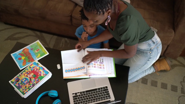 高角度的母亲帮助儿子使用笔记本电脑在家上学视频素材