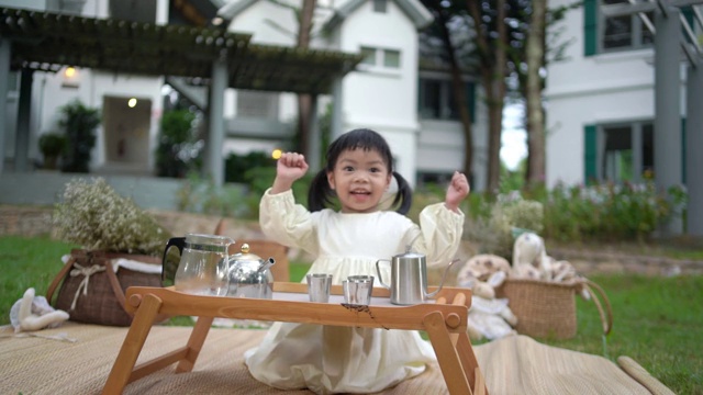 一个快乐的蹒跚学步的小孩正在花园里煮咖啡。视频素材