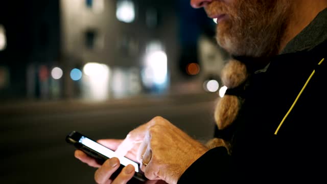 MS Hipster晚上在人行道上使用智能手机，社交媒体就会弹出点赞、评论和关注者的通知视频素材