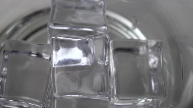 将新鲜的泉水倒入玻璃杯中的冰块上视频素材