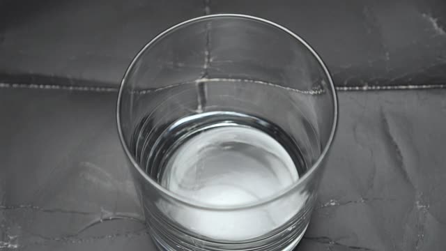 将冰块倒入玻璃杯中，然后倒入饮用的纯净水视频素材