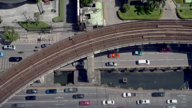 俯视图铁路轻轨与运输轨道交通列车移动在轨道桥上的汽车和车辆行驶在商业城市的地方道路上。视频素材