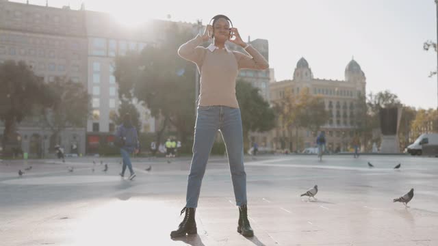 戴着耳机的年轻女子在城市里跳舞视频下载