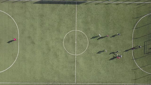 从上到下鸟瞰绿色足球场和球员踢足球。在草地上进行体育活动的小运动员。视频素材