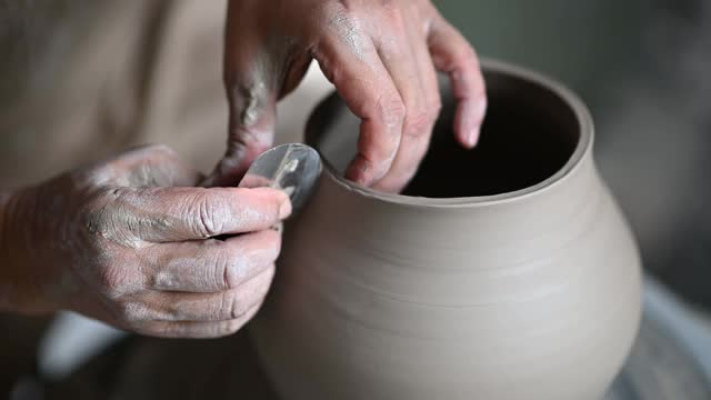 亚洲华人高级泥塑艺术家在他的工作室与纺织陶轮工作视频下载