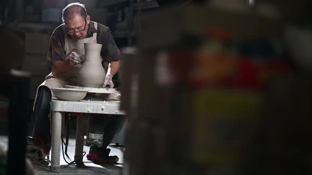 亚洲华人高级泥塑艺术家工作在他的工作室与纺织陶轮视频下载