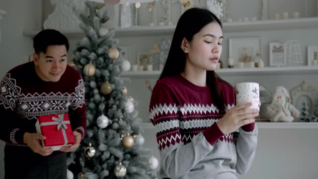 亚洲男人和女人的情人在圣诞节送礼物在他家里的客厅。视频素材