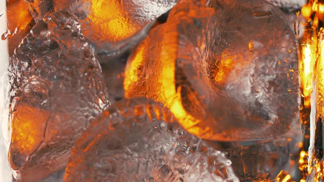 在玻璃杯里装满苏打水或红色液体的冰块的特写。鸡尾酒特写。高质量的4k慢动作镜头。视频素材