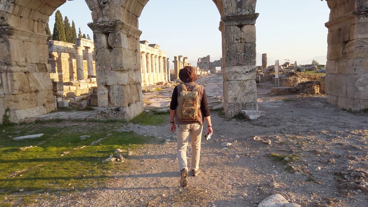 一名摄影游客正在向位于棉花堡希拉波利斯的古遗址中的Frontinus门走去视频下载