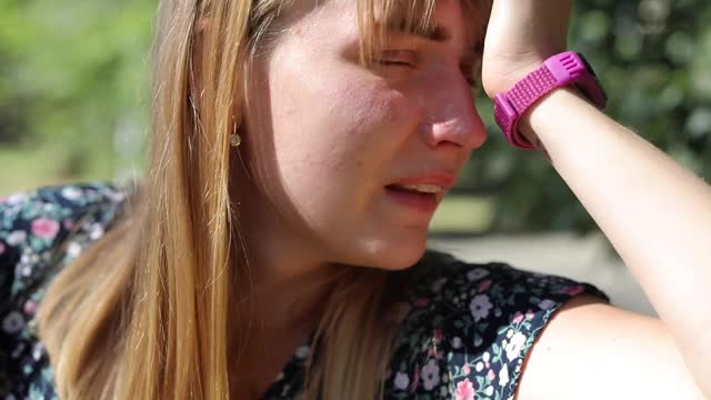 一个悲伤的女人在公园的街上哭泣视频素材