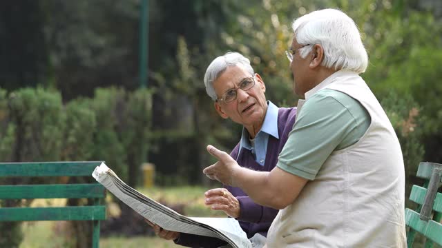 两个老人在公园里看报纸视频素材